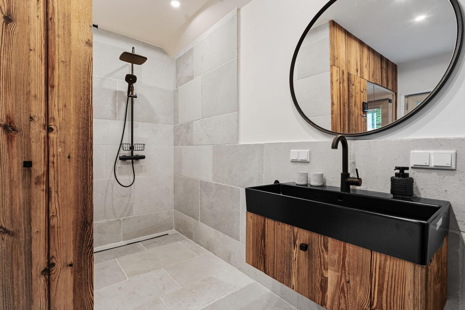 Bad mit Dusche, Waschbecken und runden Spiegel