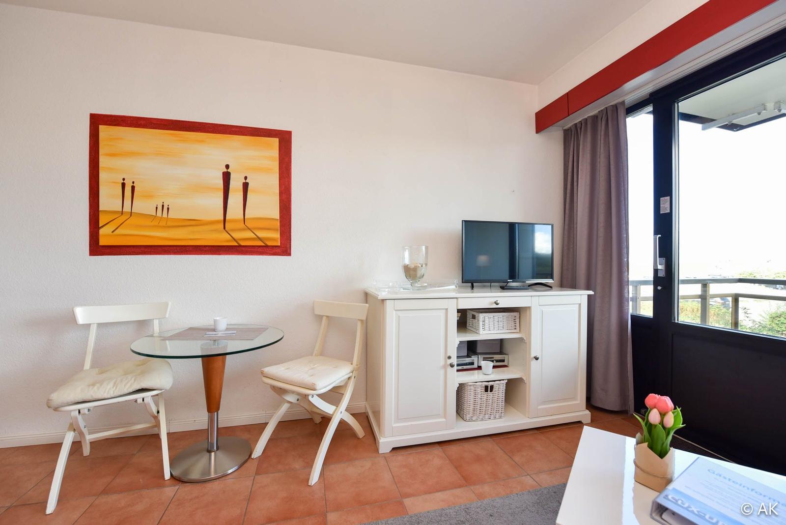 Wohnzimmer mit Esstisch, TV-Schrank und Balkontür.