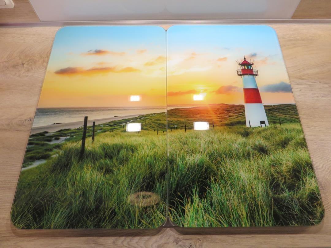 Ein Bodenbelag mit Motiv eines Leuchtturms an der Küste bei Sonnenuntergang.