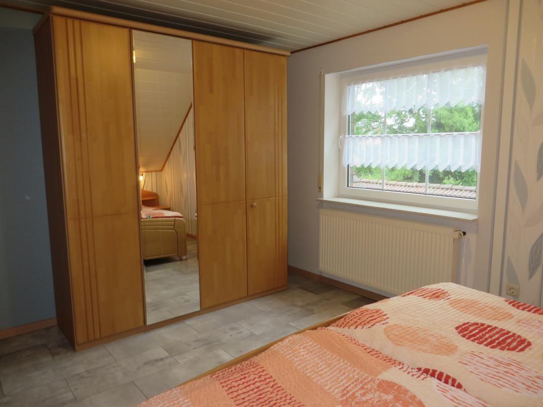 Schlafzimmer mit Kleiderschrank, Fenster und Bett.
