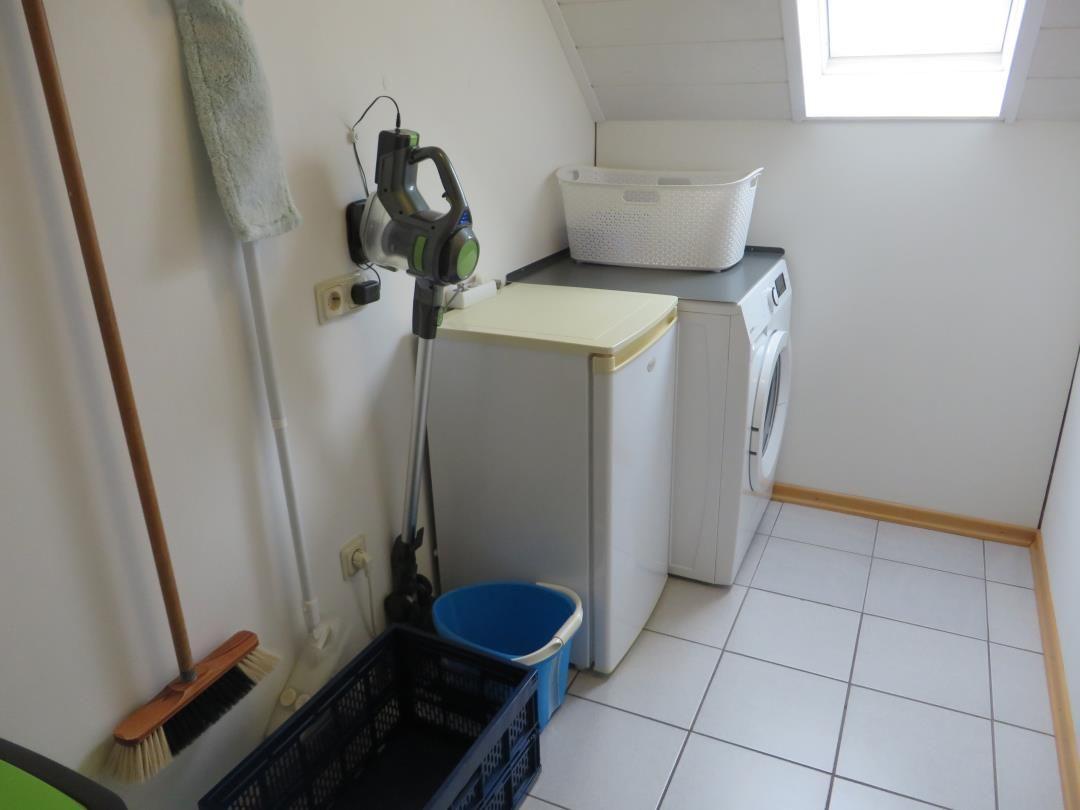 Waschraum mit Waschmaschine, Wäschekorb und Staubsauger.