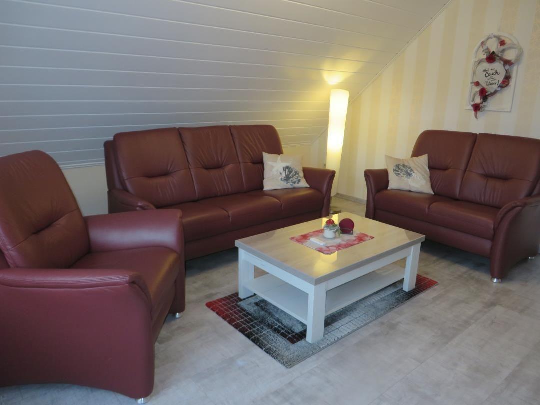 Wohnzimmer mit zwei Sofas, Sessel und Couchtisch auf Teppich