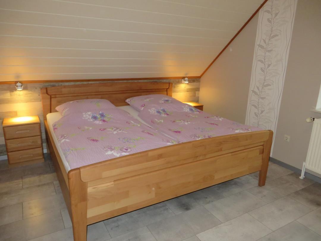 Schlafzimmer mit Holzbett, Nachttischen und gemütlicher Beleuchtung.