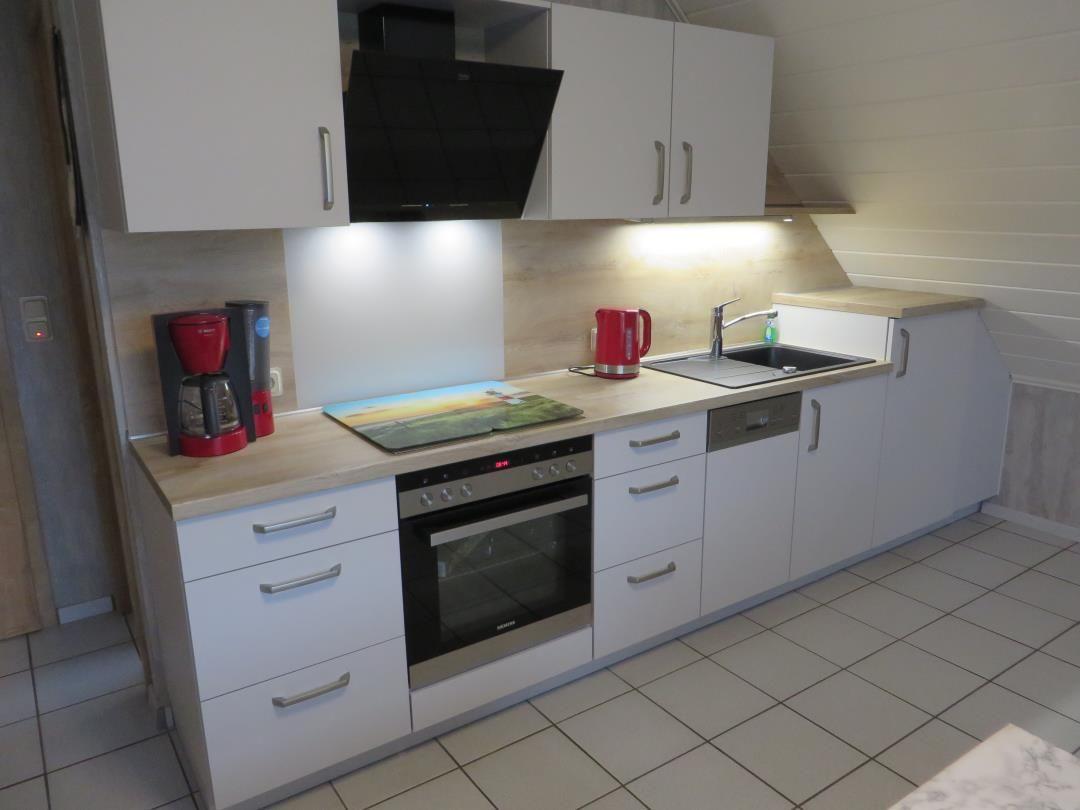 Küche mit weißen Schränken, Edelstahlherd und rotem Wasserkocher.