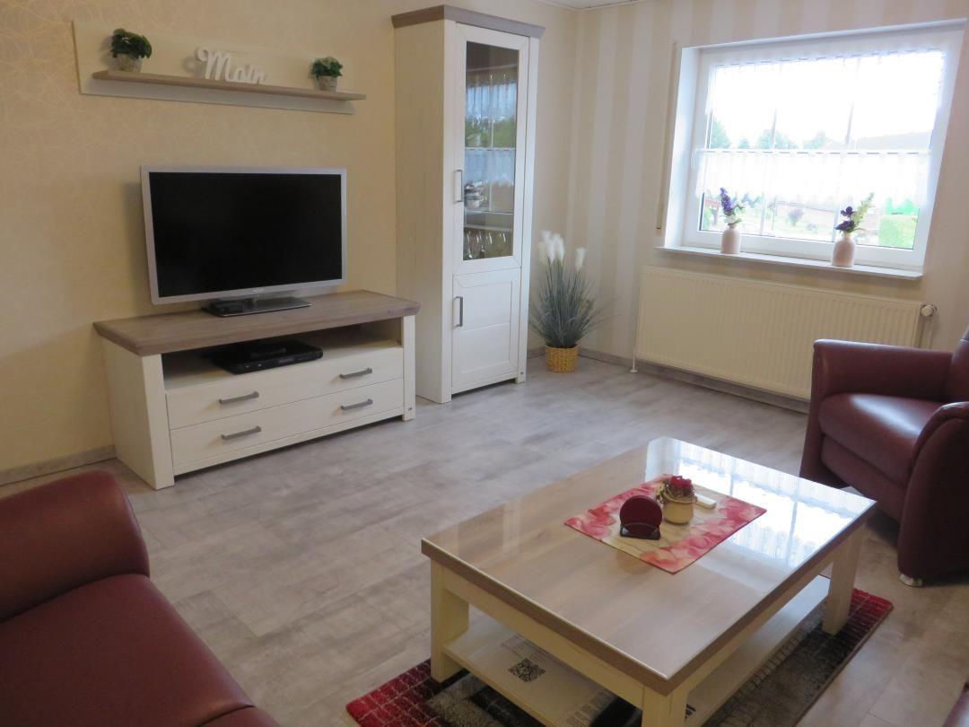 Wohnzimmer mit Fernseher, Couch, Tisch und Fenster.