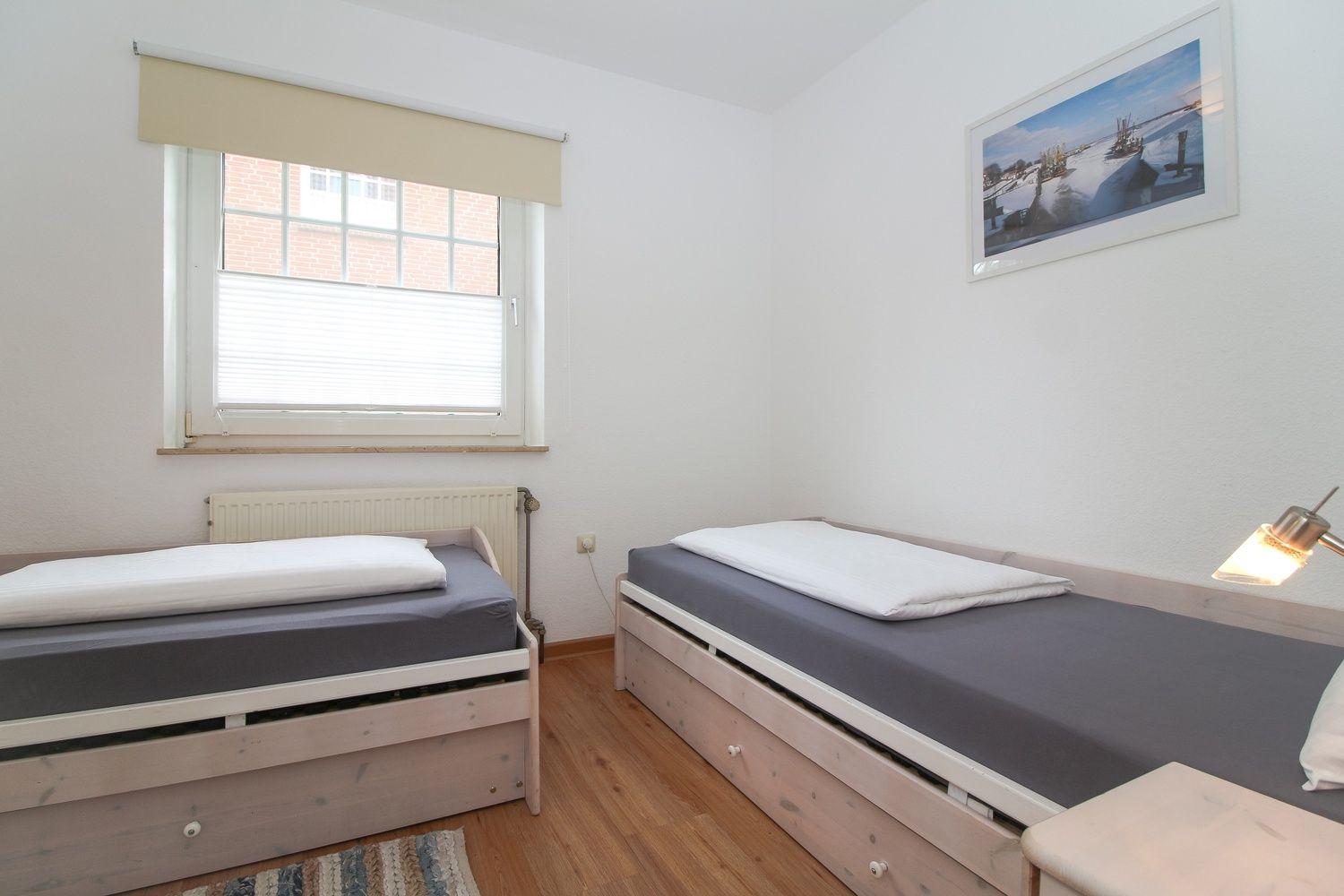 Zimmer mit zwei Einzelbetten, Fenster und Wandbild.