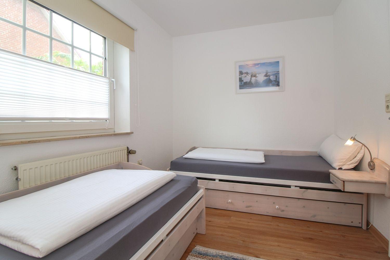 Zimmer mit zwei Betten, Fenster und Wandbild.