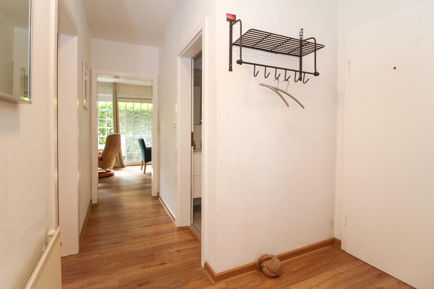 Flur mit Holzboden, Garderobe und Blick in Wohn- und Schlafzimmer.