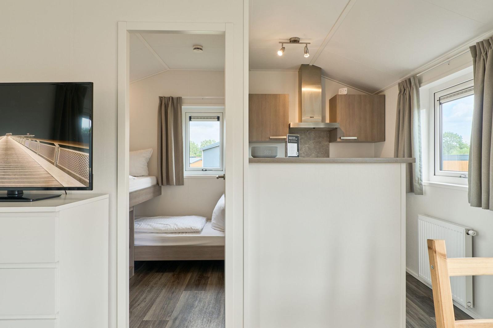 Küche mit Arbeitsplatte und Fenster. Schlafzimmer mit Bett und Fenster.