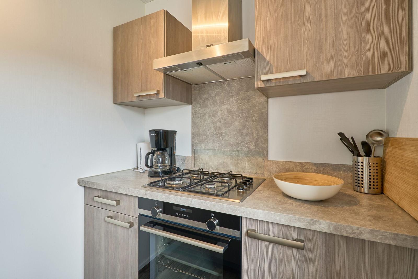 Küche mit Kochfeld, Backofen und Dunstabzug.