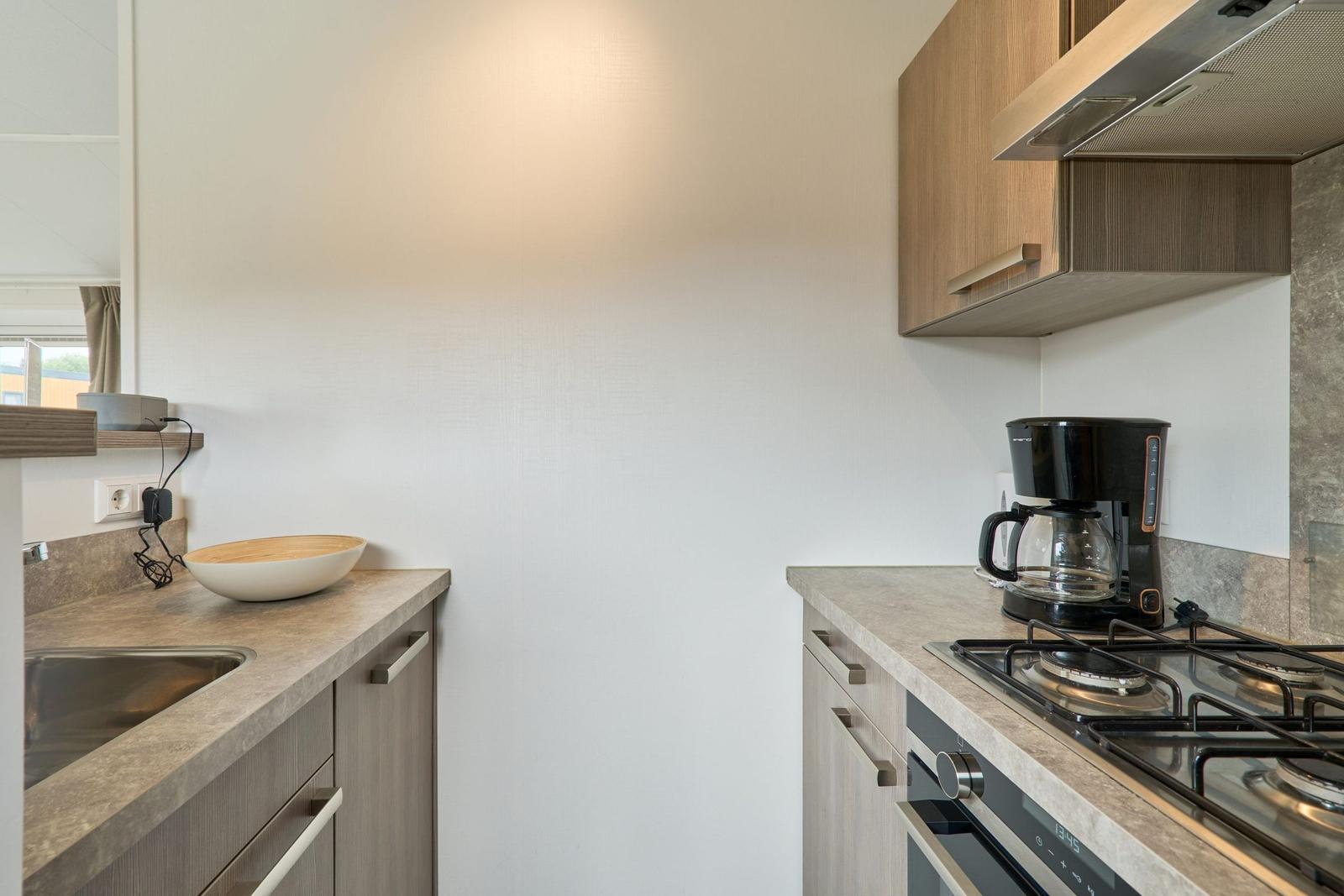 Küche mit Spüle, Kochfeld und Kaffeemaschine.