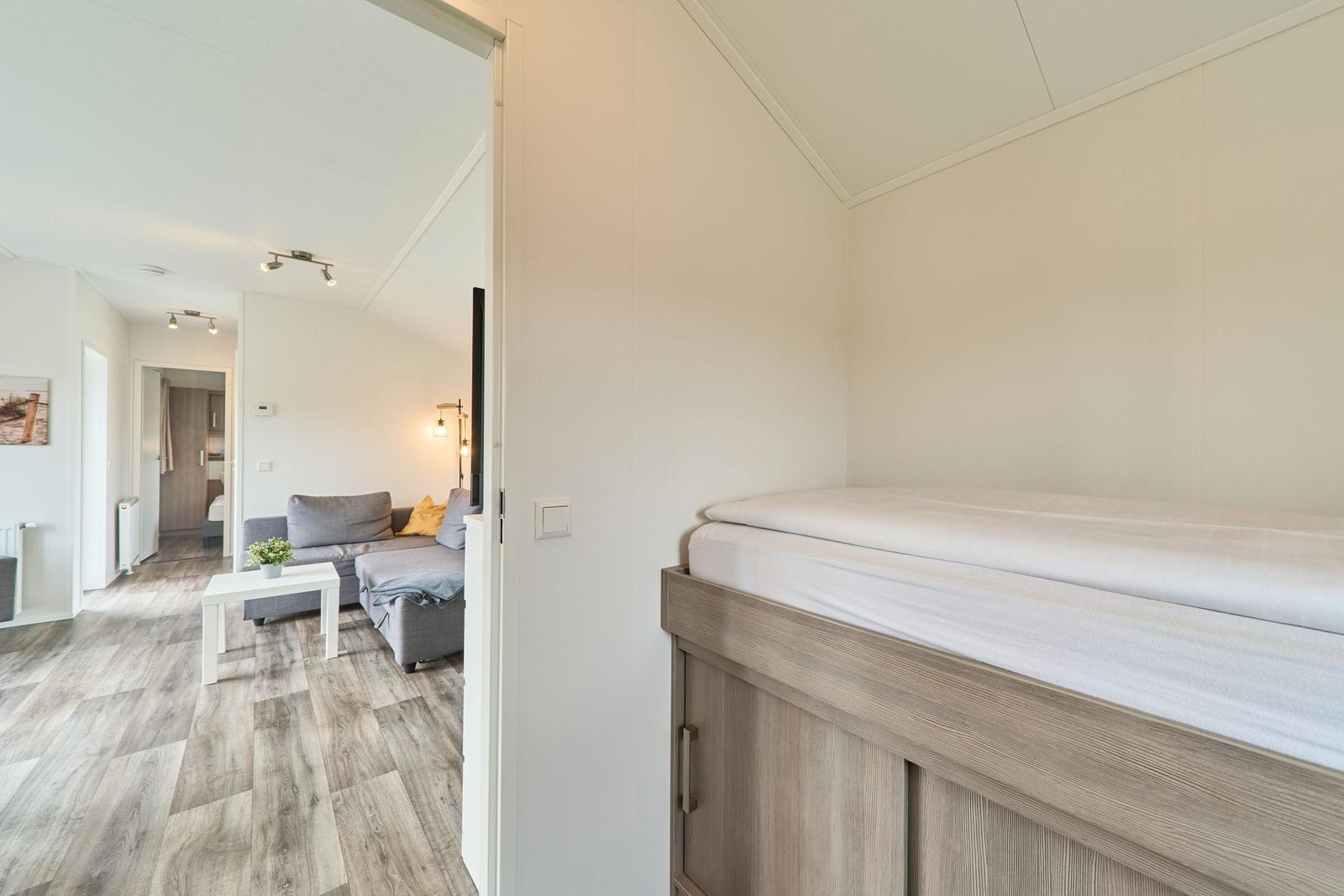 Schlafzimmer mit Doppelbett und Sicht auf Wohnbereich mit Sofa.