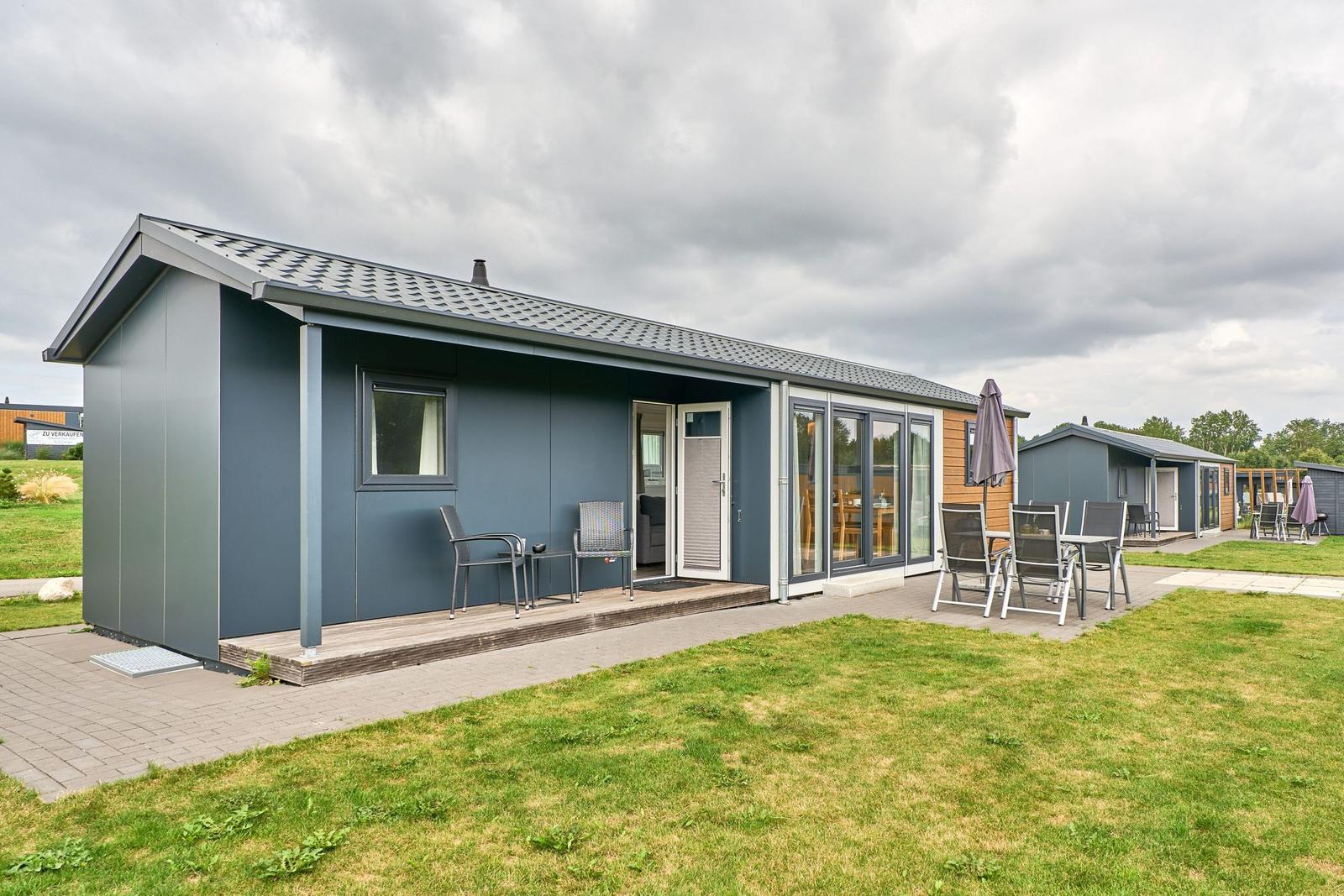 Moderne Ferienhaus mit Terrasse und Garten. Glastüren führen ins Innere.