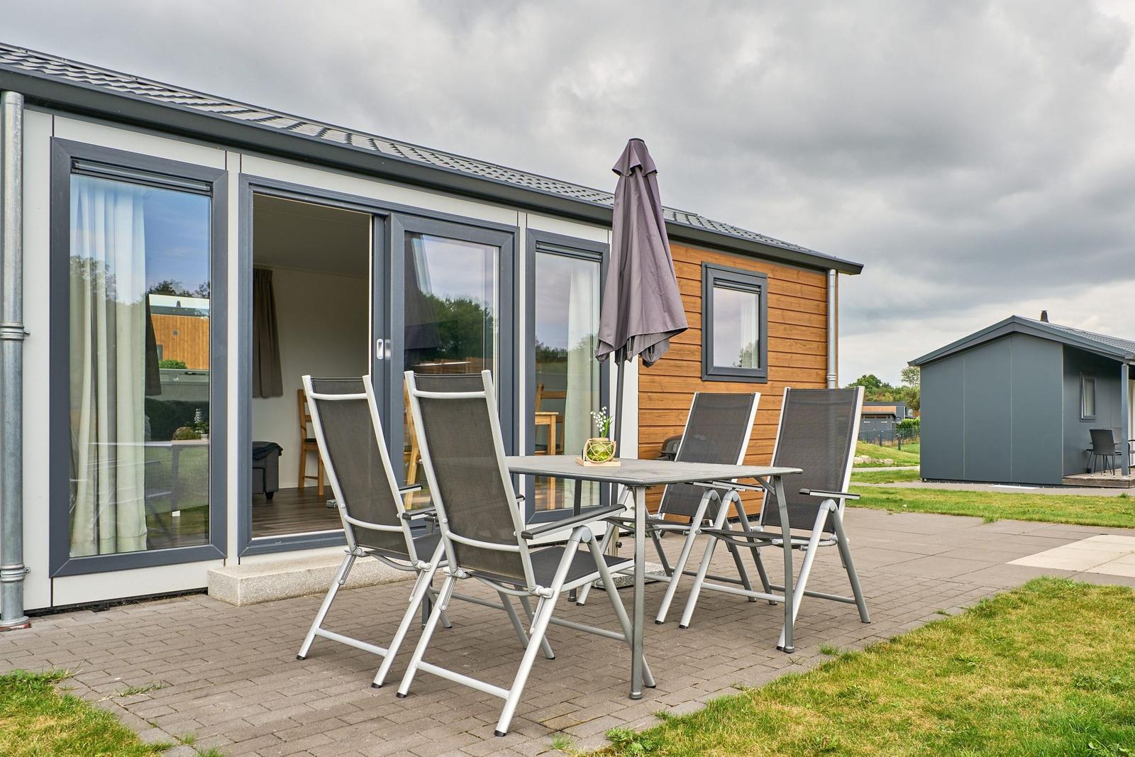 Terrasse mit Tisch und Stühlen vor modernem Ferienhaus.