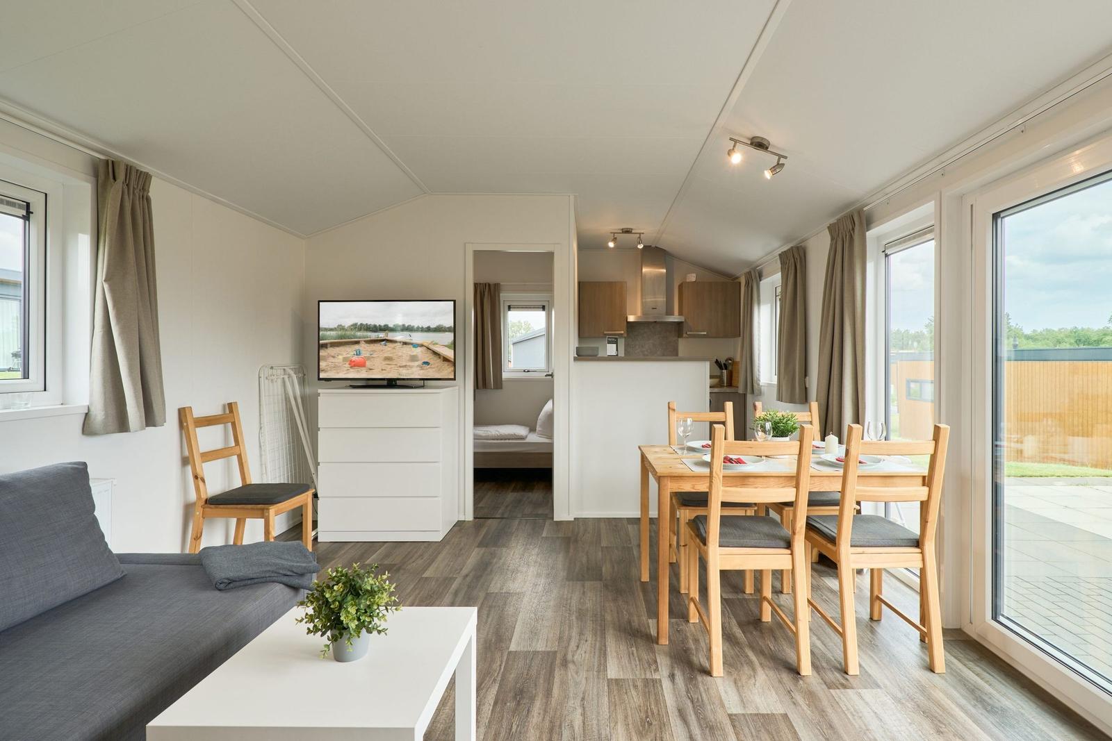 Wohn- und Essbereich mit Küche und Schlafzimmer im Hintergrund.