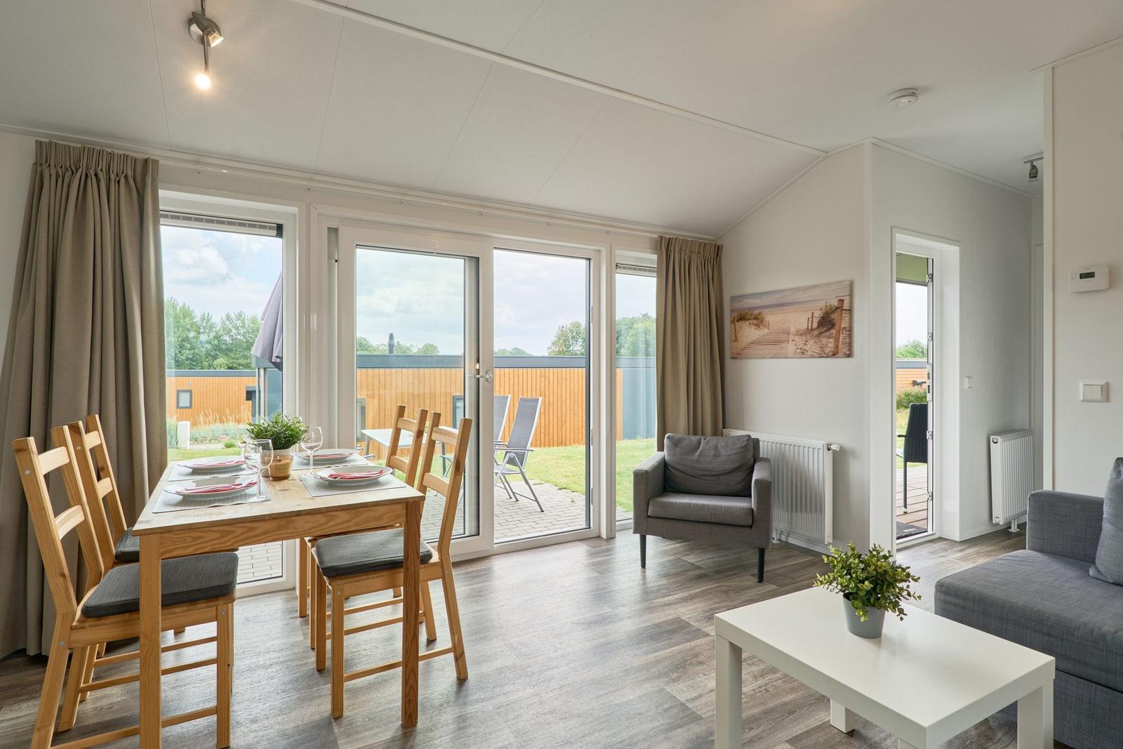 Wohn- und Essbereich mit Tisch, Stühlen und Sitzgelegenheiten. Durchgang zur Terrasse.