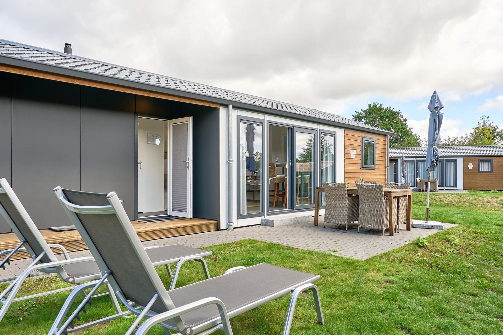 Moderne Ferienwohnung mit Terrasse, Liegen und Essgruppe im Freien.