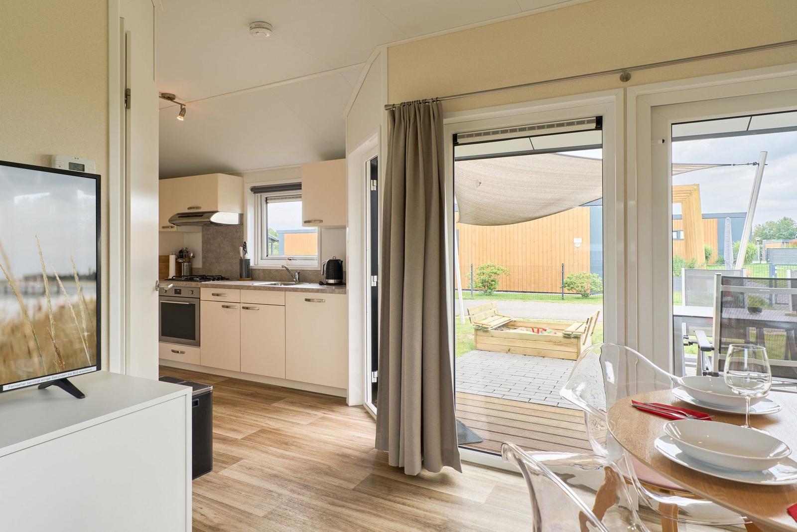 Küche, Essbereich und Terrasse mit Gartenmöbeln und Sonnensegel.