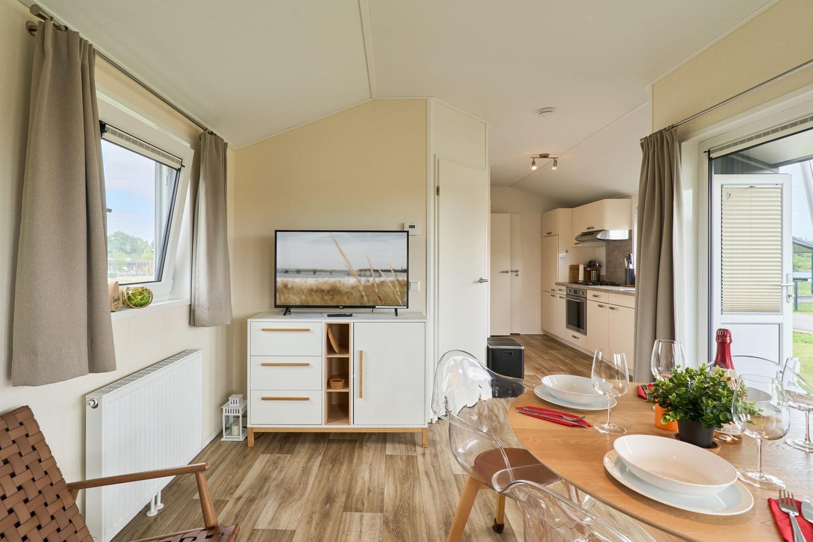 Wohn- und Essbereich mit TV, Esstisch und Blick auf die Küche.