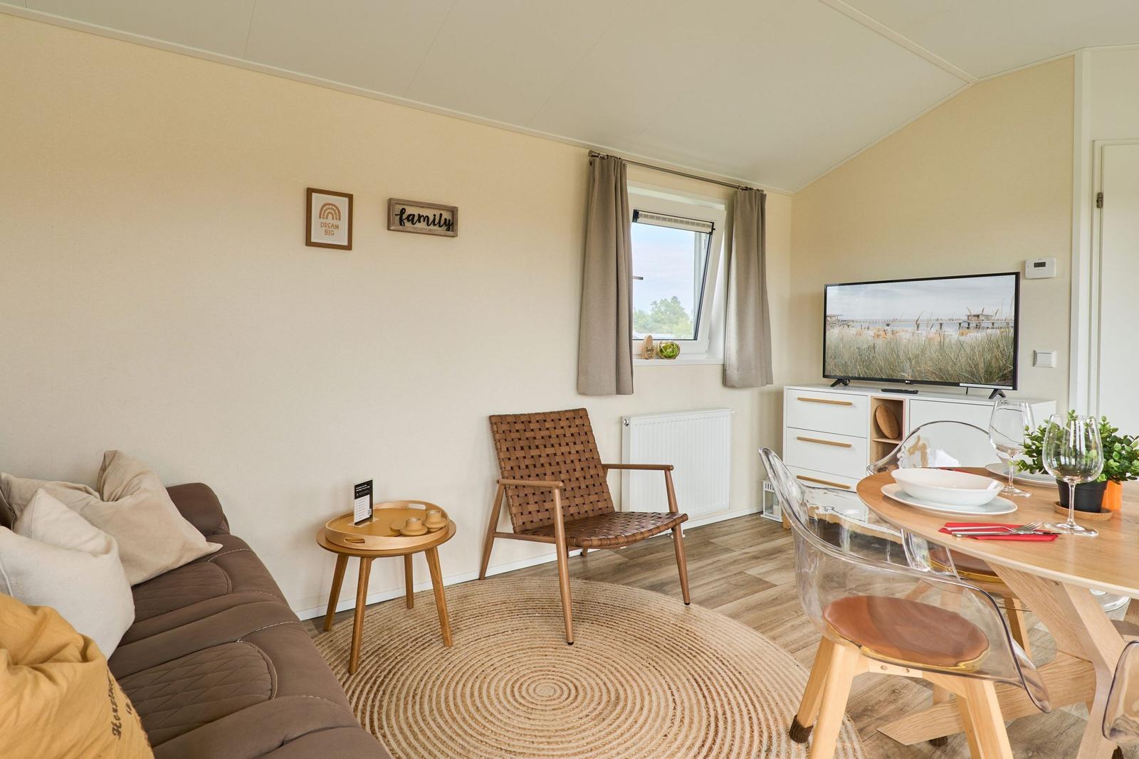 Wohn- und Essbereich mit Sofa, Stuhl, TV und Tisch.