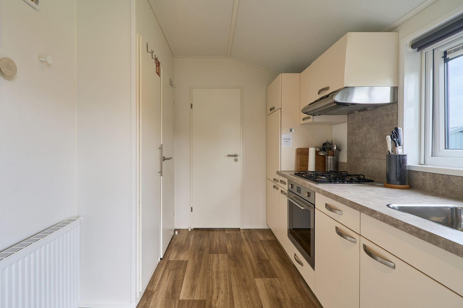 Küche mit Arbeitsplatte, Herd, Spüle und Fenster