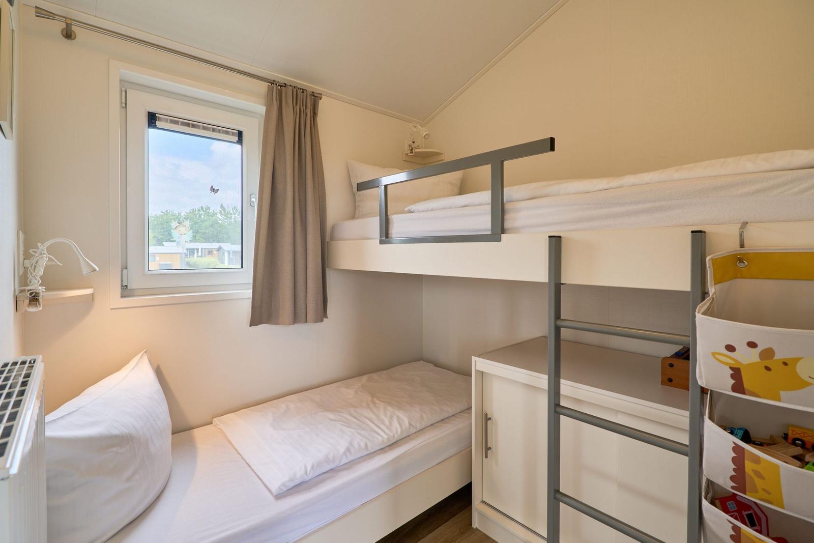 Zimmer mit Doppelstockbett, Fenster und Spielzeugkorb.