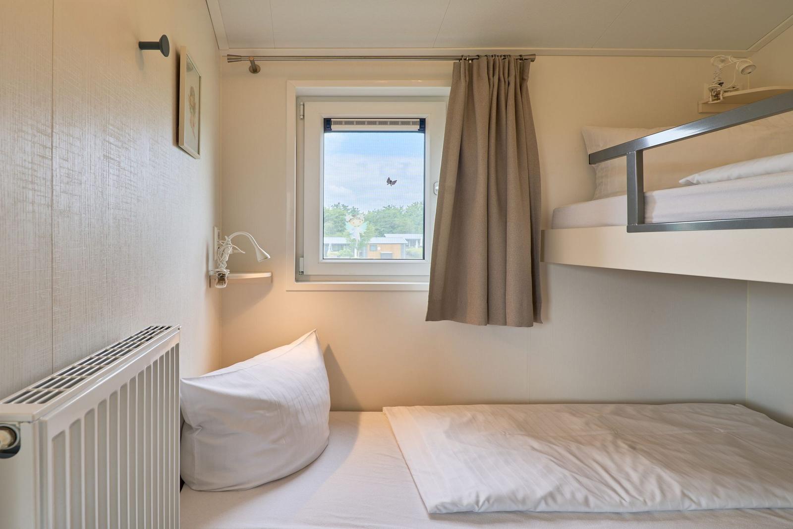 Zimmer mit Doppelstockbett, Fenster und Heizung.