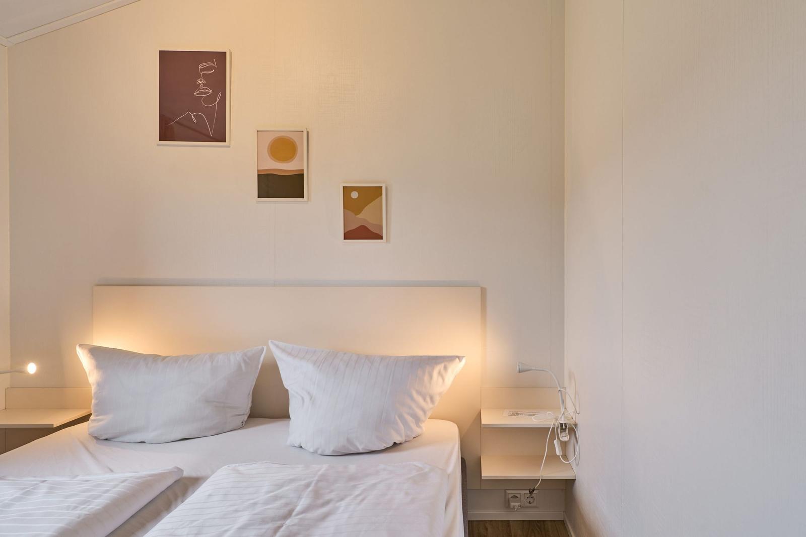 Ein Bett mit zwei Kissen und Wandbildern über dem Kopfteil.