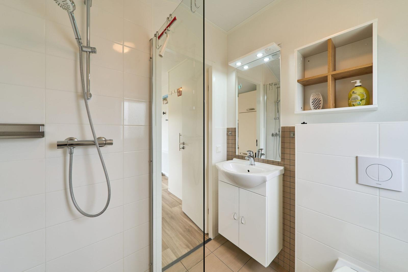 Badezimmer mit Dusche, Waschbecken und Spiegelschrank.