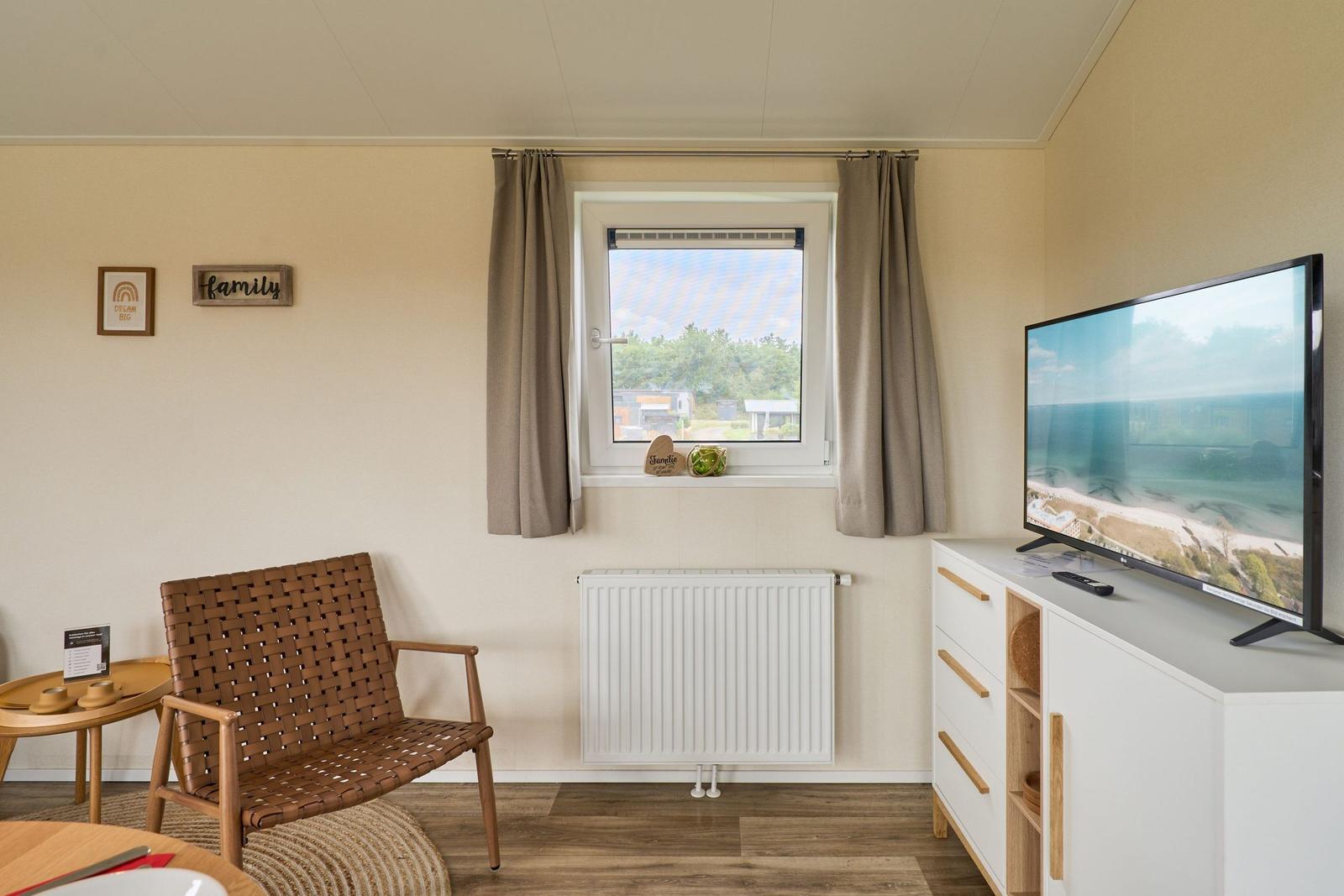 Ein Raum mit einem Fenster, einem Fernseher und einem Stuhl.