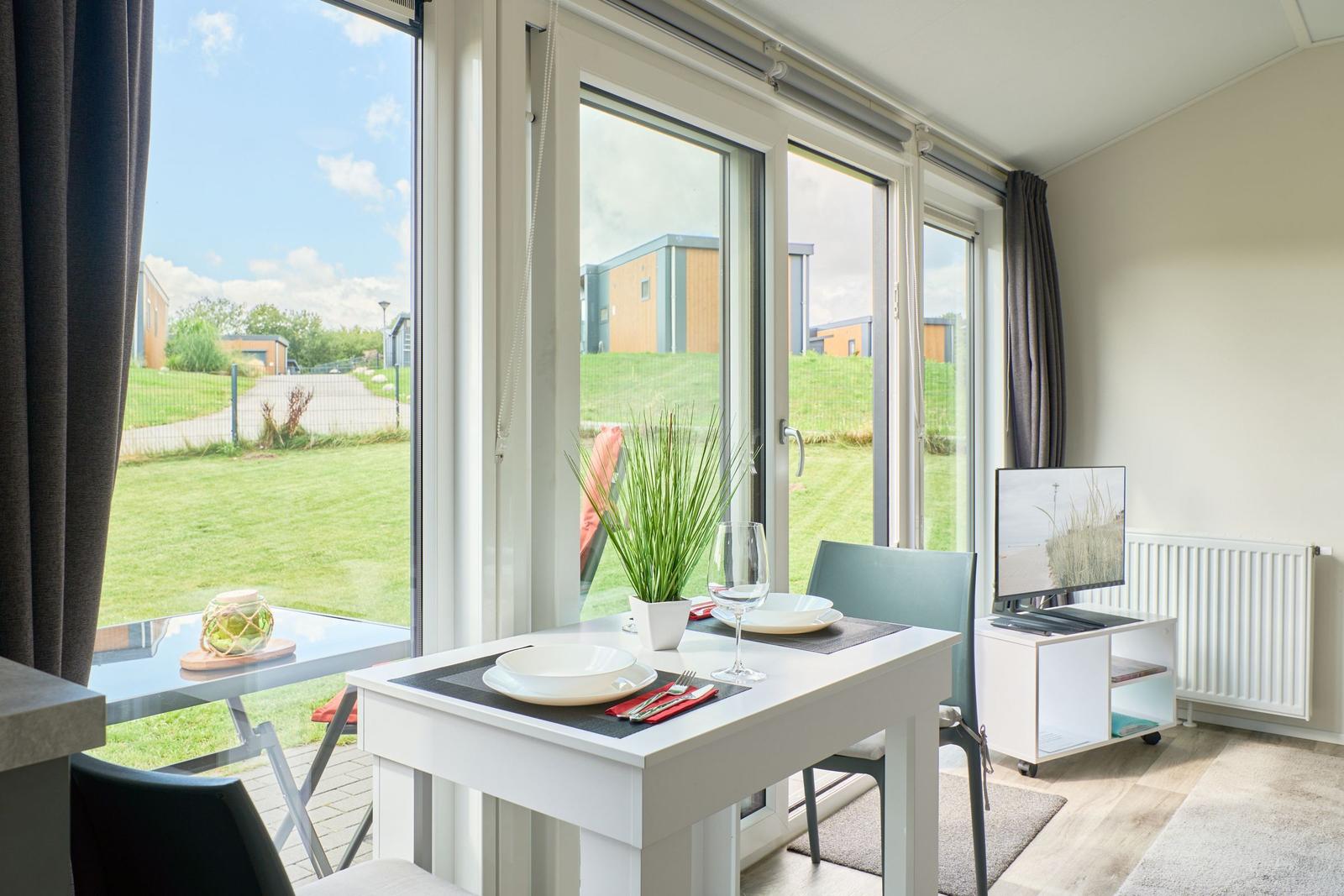 Esstisch mit Platz für zwei, großes Fenster mit Blick auf Grünfläche.