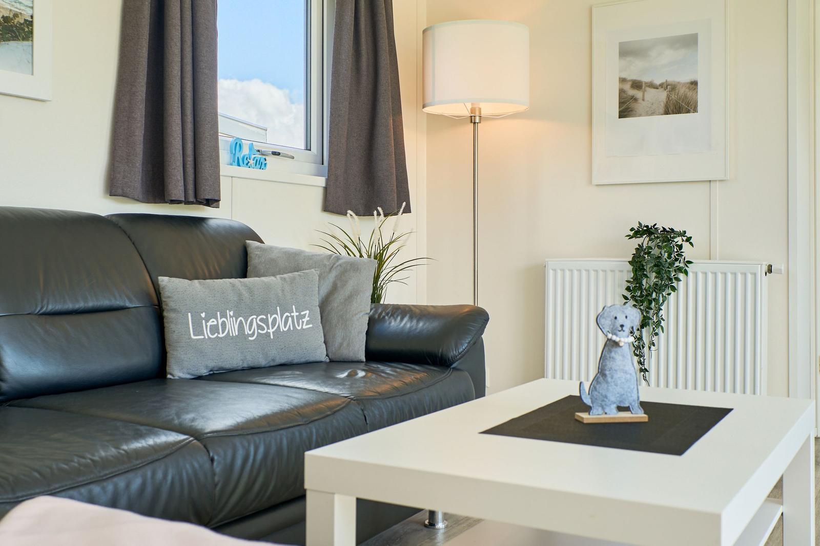 Schwarzes Sofa mit Kissen, weißer Couchtisch und Stehlampe im Wohnzimmer.