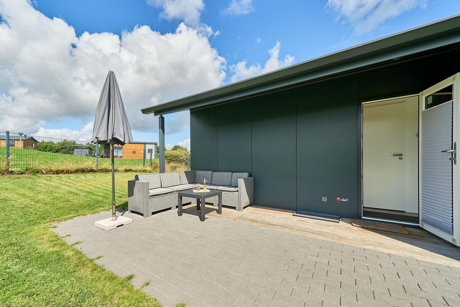 Terrasse mit Sitzgruppe, Sonnenschutz und Zugang zur Unterkunft.