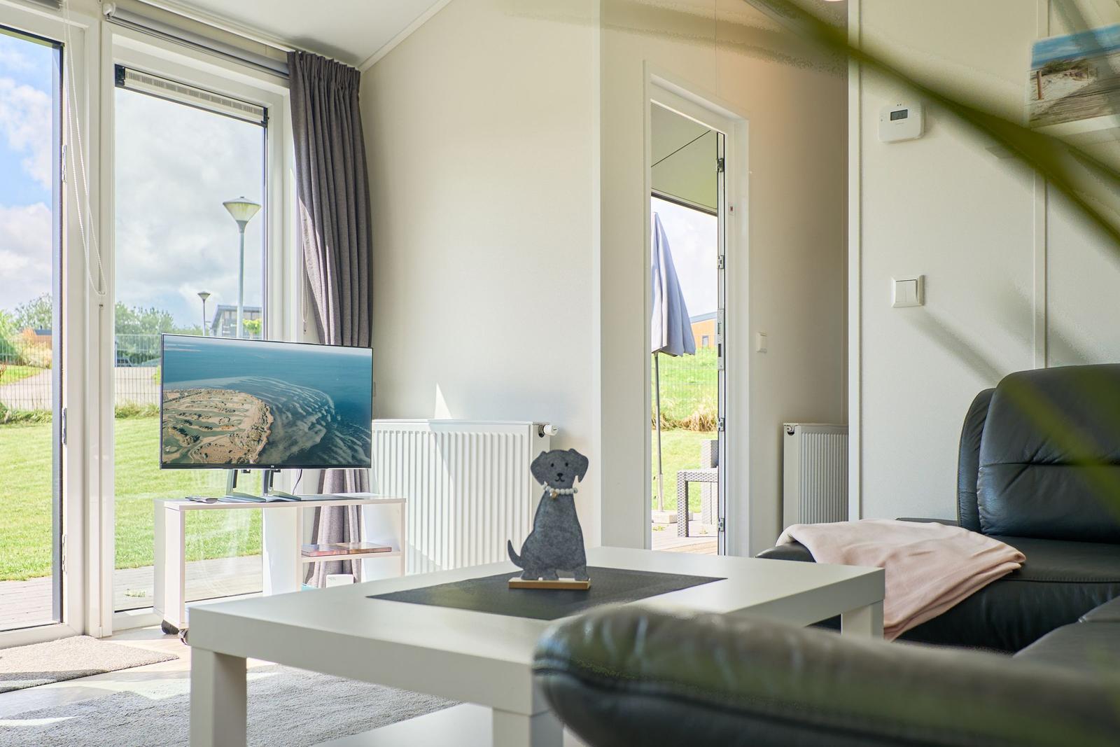 Wohnzimmer mit TV, Couch und Blick auf Garten