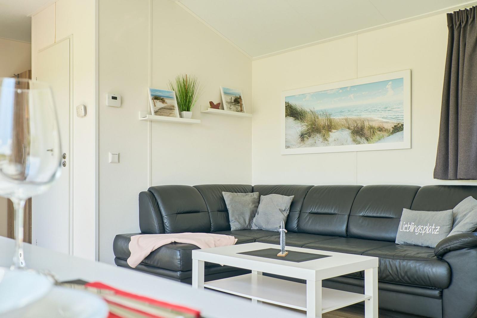 Ein Wohnzimmer mit einem schwarzen Sofa, einem weißen Tisch und Wandbildern.