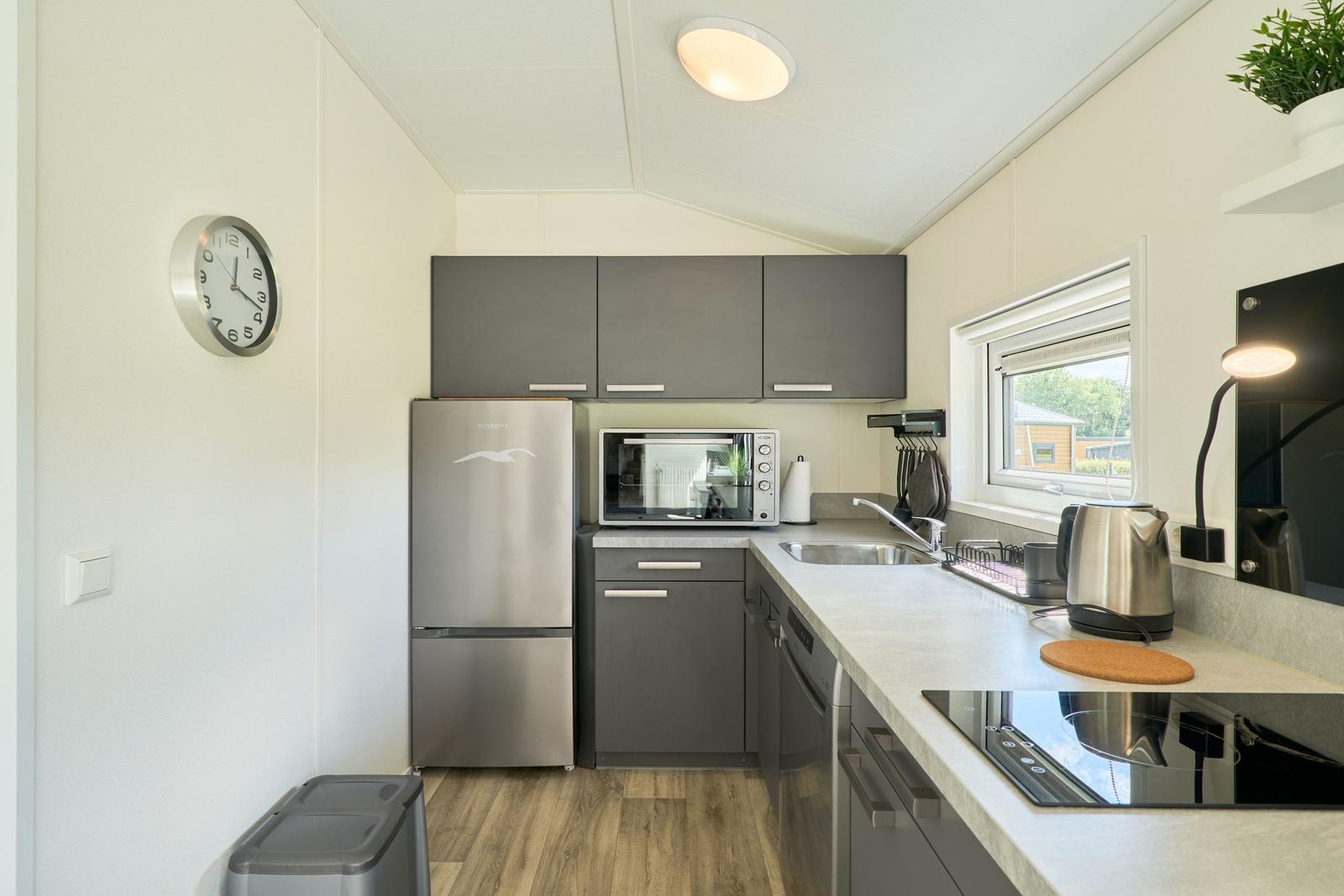 Küche mit Kühlschrank, Spüle und Kochfeld.