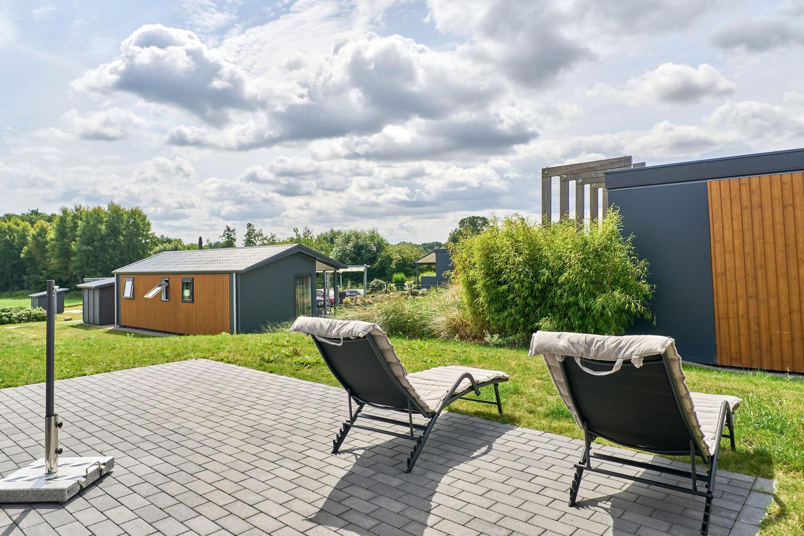 Terrasse mit zwei Liegestühlen und Blick auf moderne Häuser.