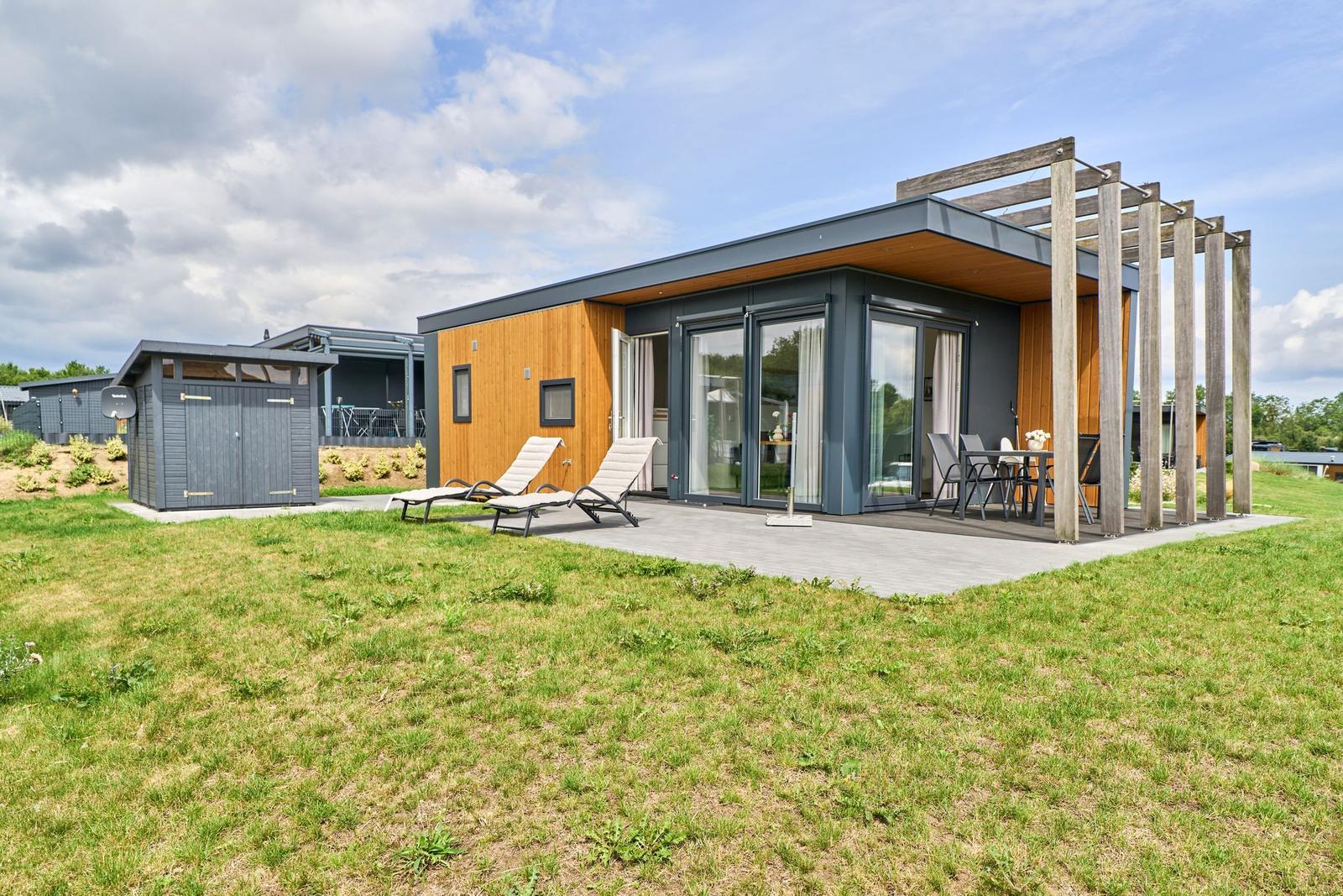 Moderne Ferienhaus mit Terrasse, Sonnenliegen und Holzüberdachung.