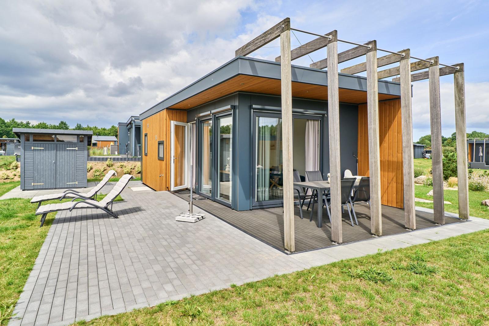 Moderne Unterkunft mit Terrasse, Sitzgelegenheiten und Gartenbereich.