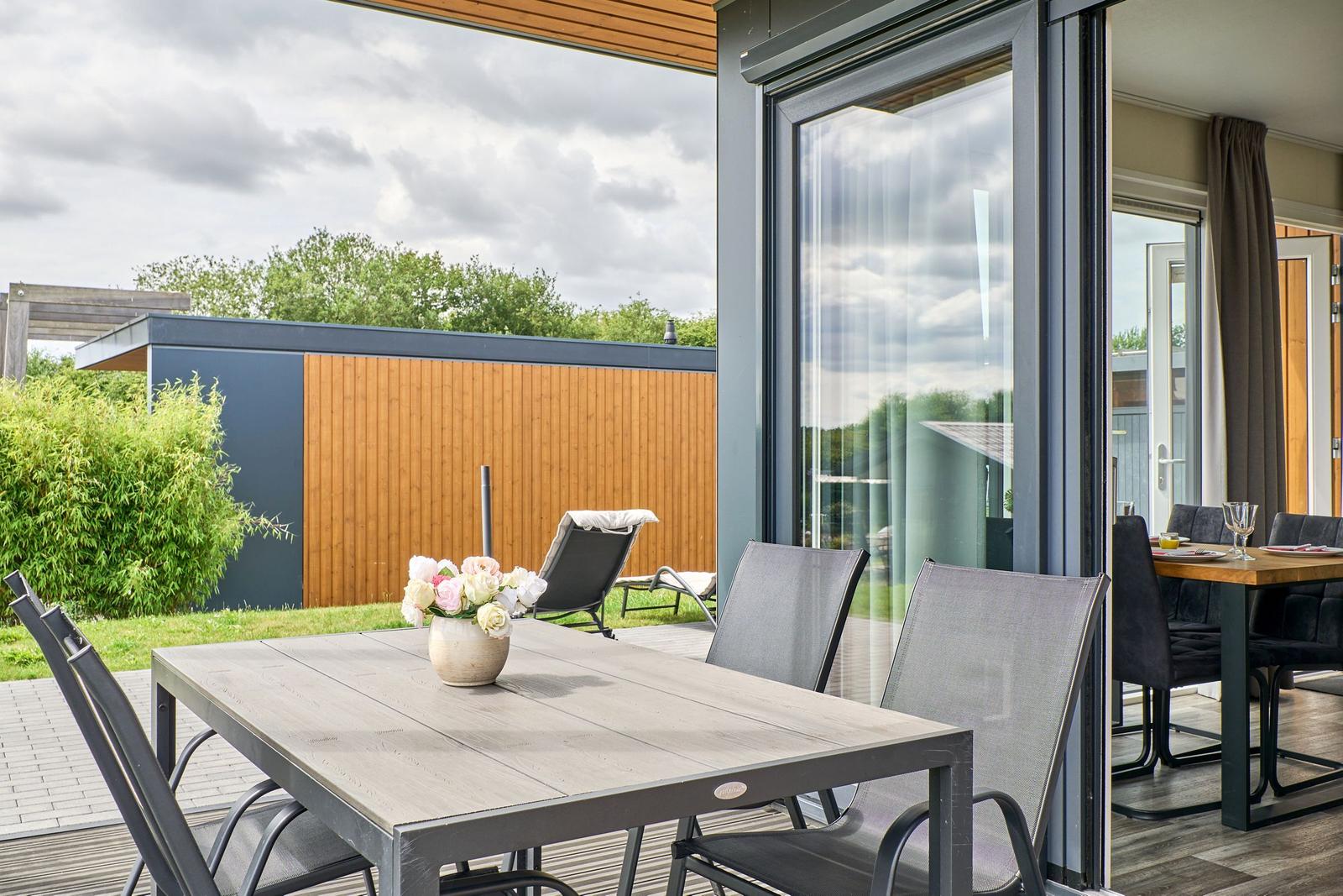 Terrasse mit Tisch und Stühlen, Blick auf Garten und Haus.
