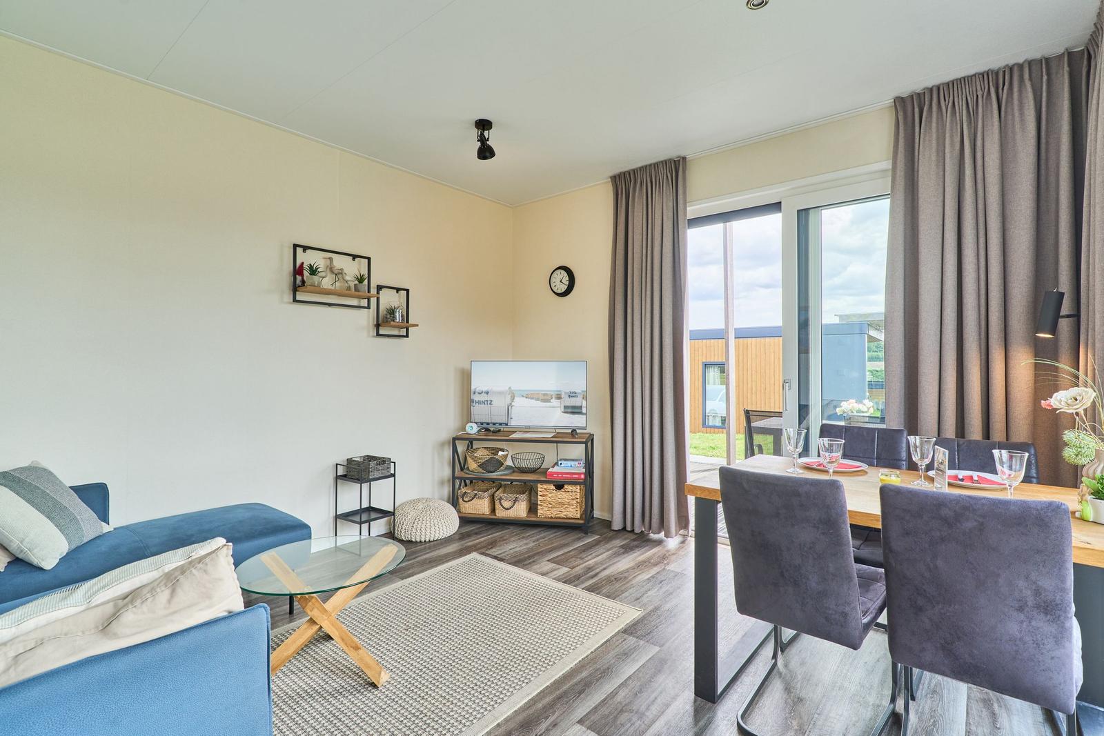 Wohn- und Essbereich mit Sofa, TV und Terrassentür.