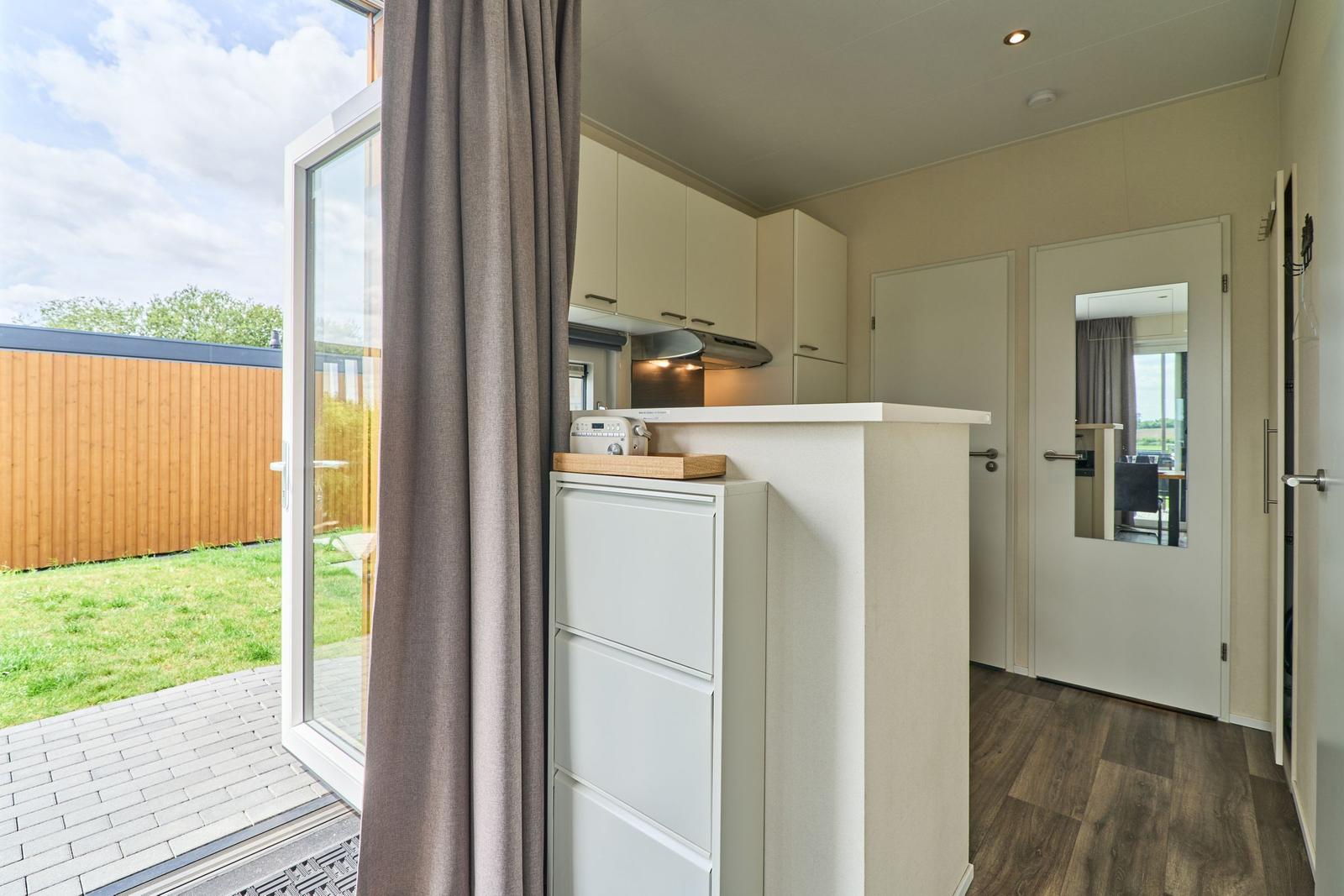 Küche mit Blick auf den Garten. Weiße Schränke und Holzboden.