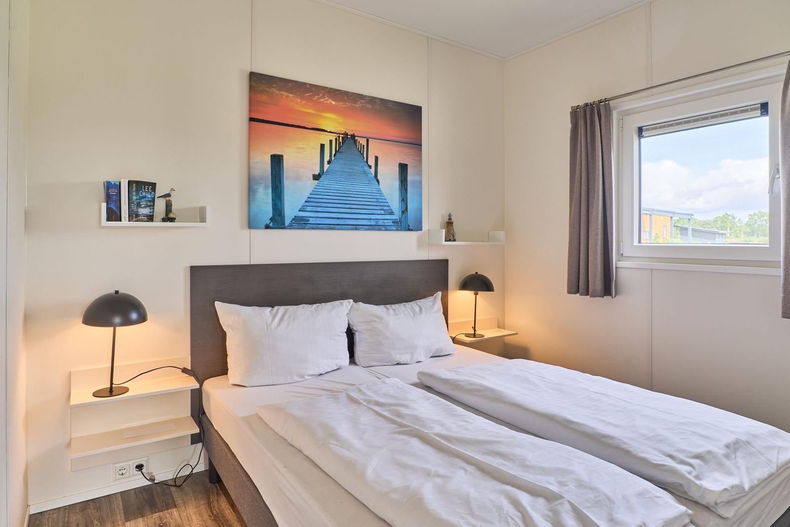 Schlafzimmer mit Doppelbett, Wandbild und Fenster mit Blick.