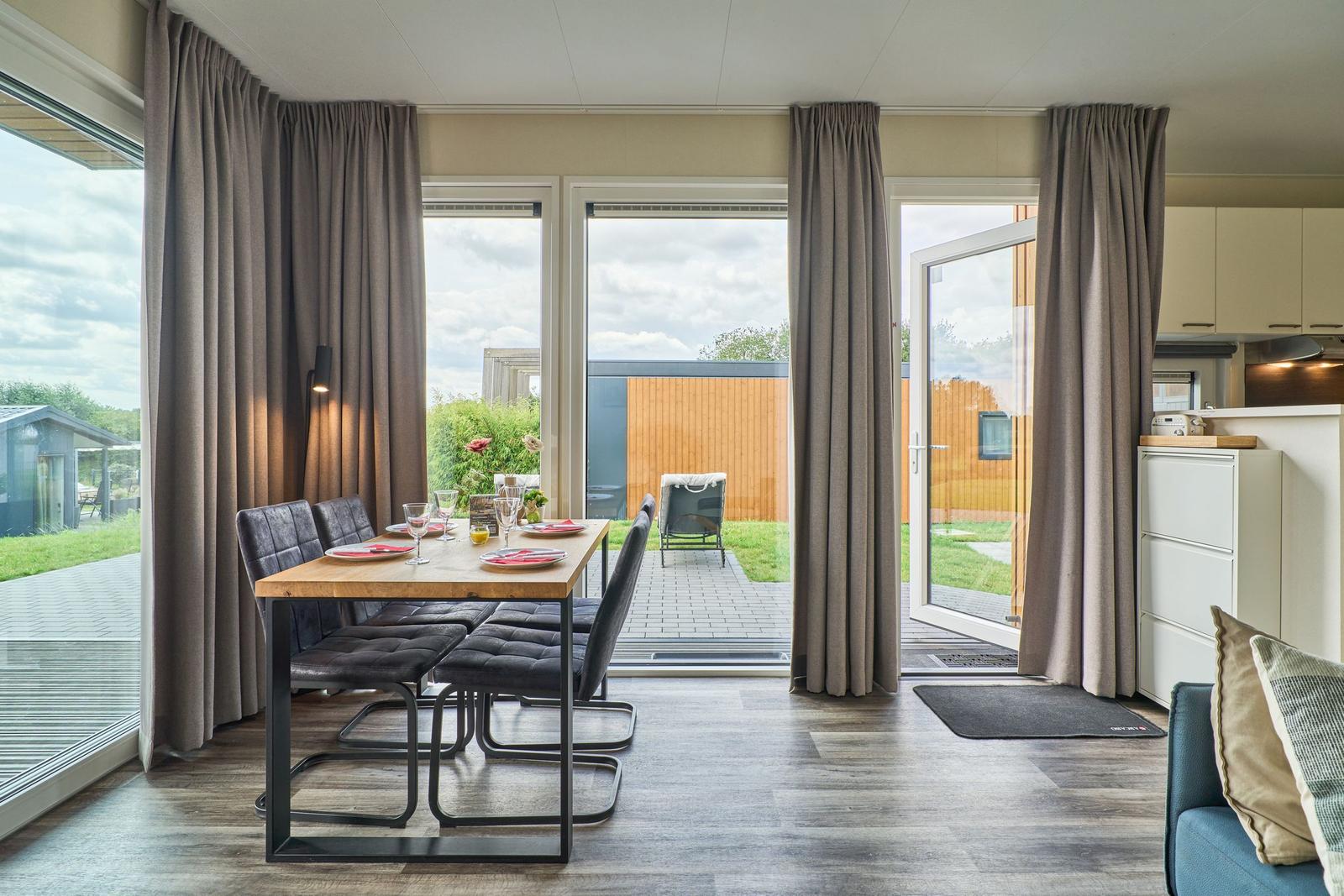 Essbereich mit Tisch und Stühlen. Durchgehendes Fenster mit Blick auf Terrasse.