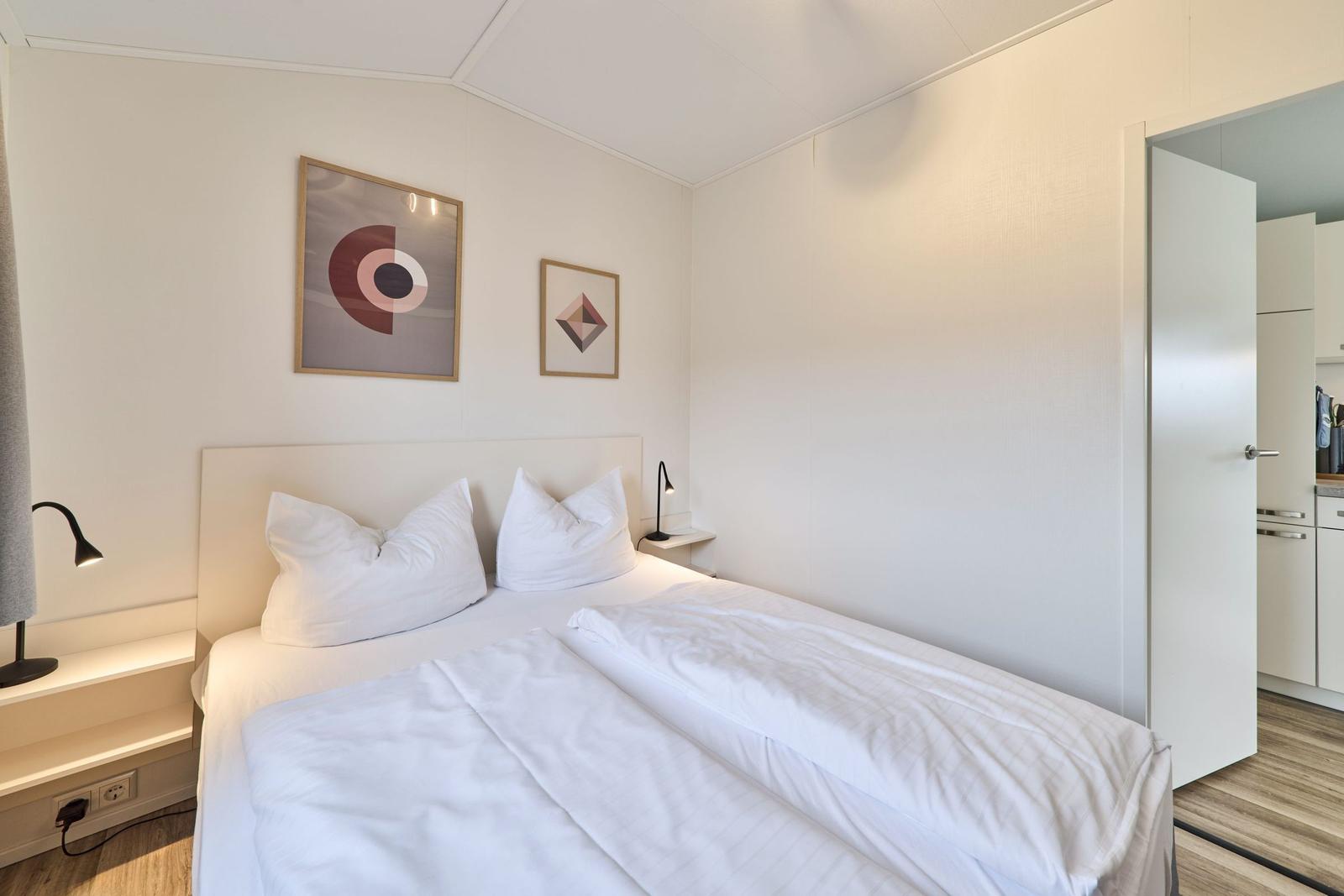 Schlafzimmer mit Doppelbett, zwei Nachttischen und Wandbildern.