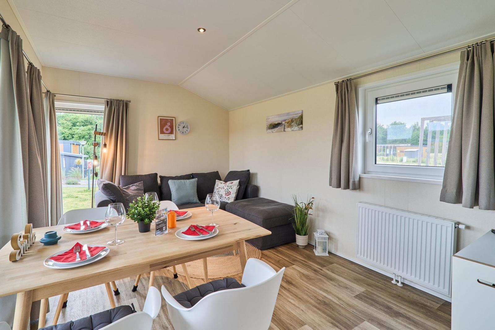 Essbereich mit Tisch, Stühlen und Sofa. Fenster und Vorhänge sichtbar.