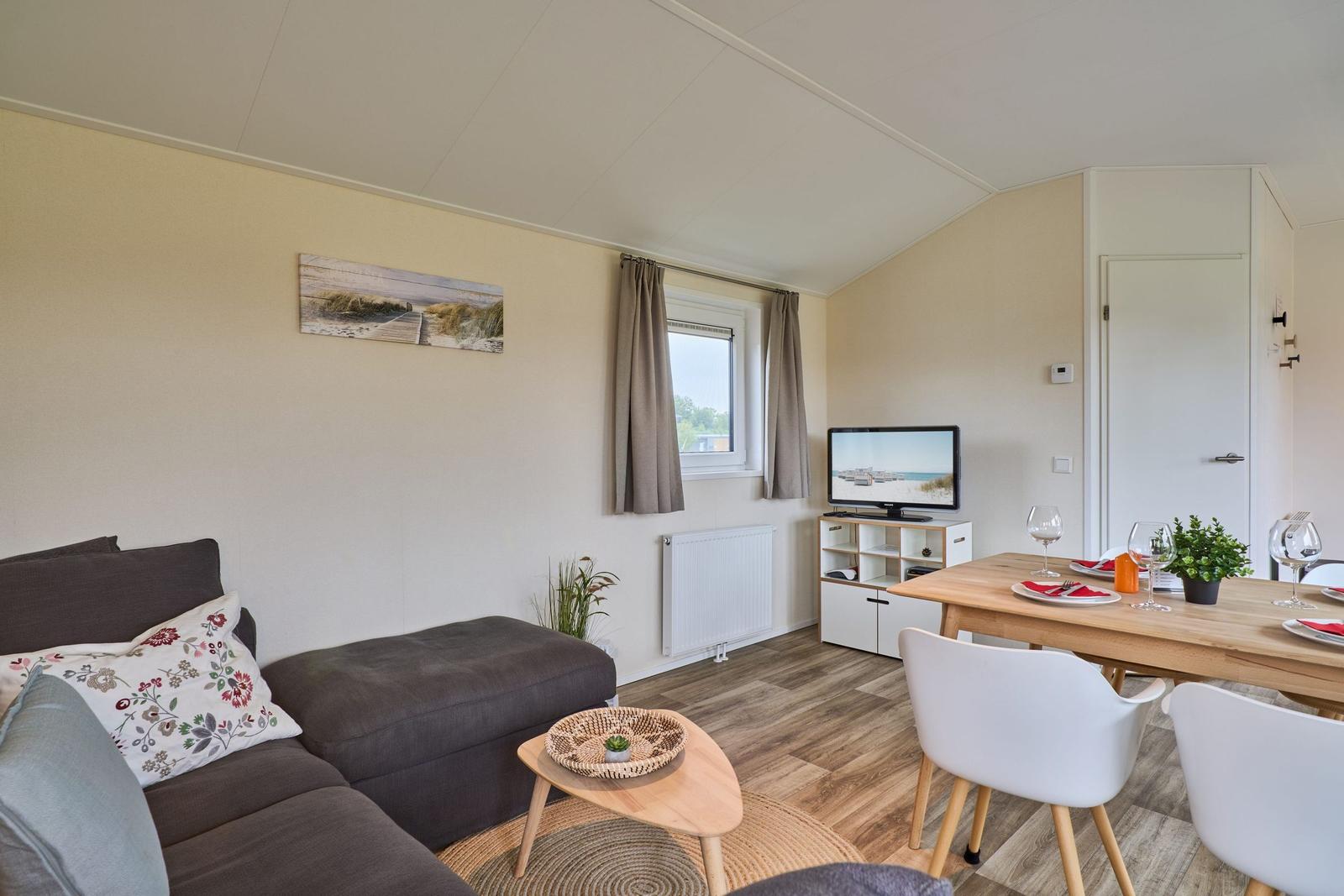 Wohn- und Essbereich mit Sofa, TV und Esstisch mit Stühlen.