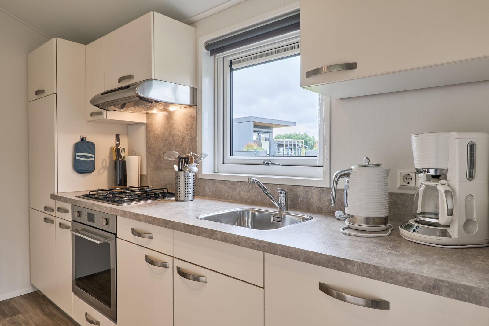 Küche mit Arbeitsplatte, Spüle, Herd und Fenster.