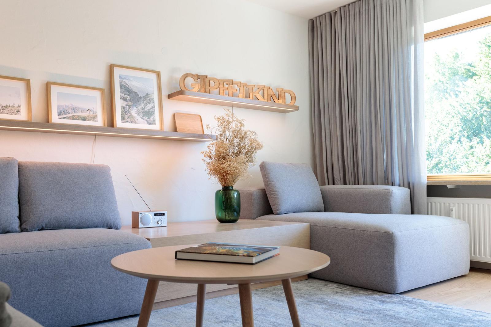 Wohnzimmer mit Sofa, Tisch und Wandregal mit Bildern und Dekoration.