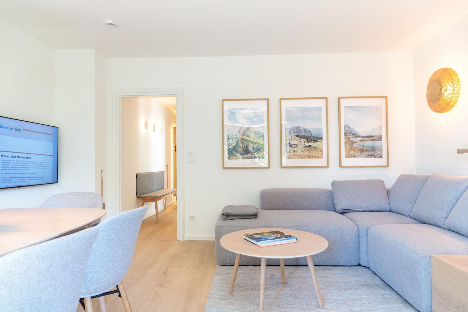 Wohnbereich mit Sofa, Tisch und Wandbildern